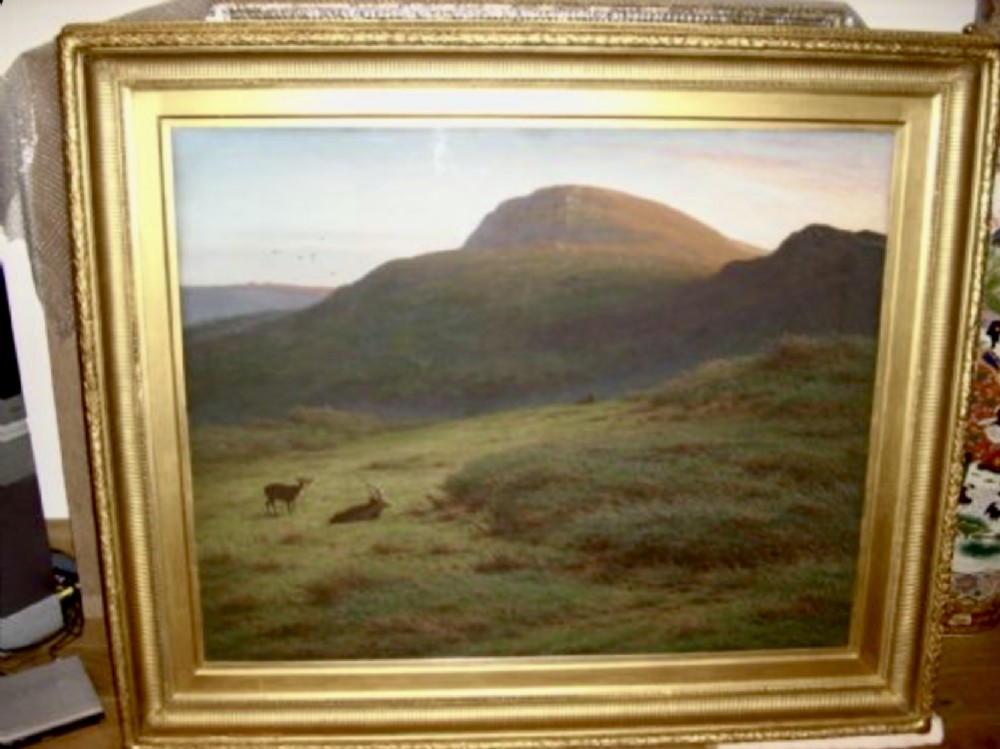 A large framed landscape painting depicting rolling green hills and deer under a muted sky within a moulded gold gilt frame. View V