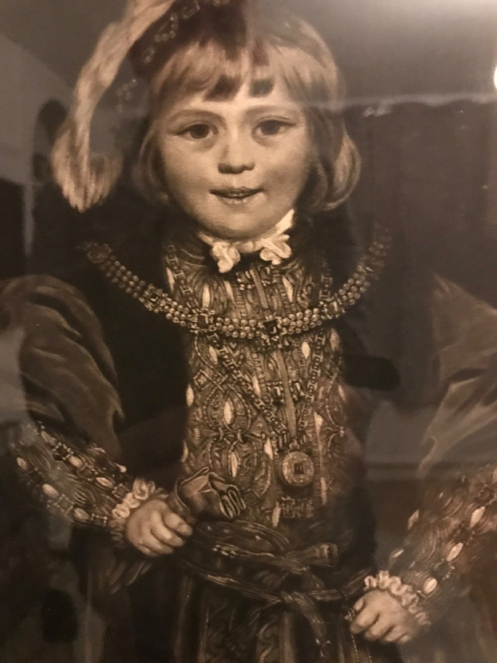 A framed black and white mezzotint print depicting a young boy in historical dress posing as Henry VIII. View VII
