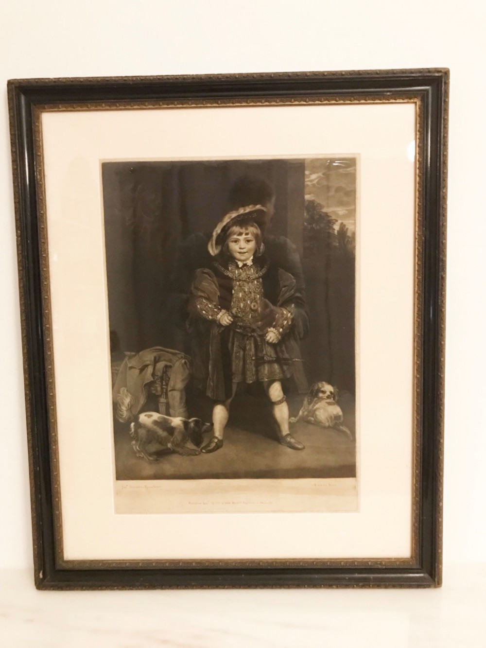 A framed black and white mezzotint print depicting a young boy in historical dress posing as Henry VIII. View XIII