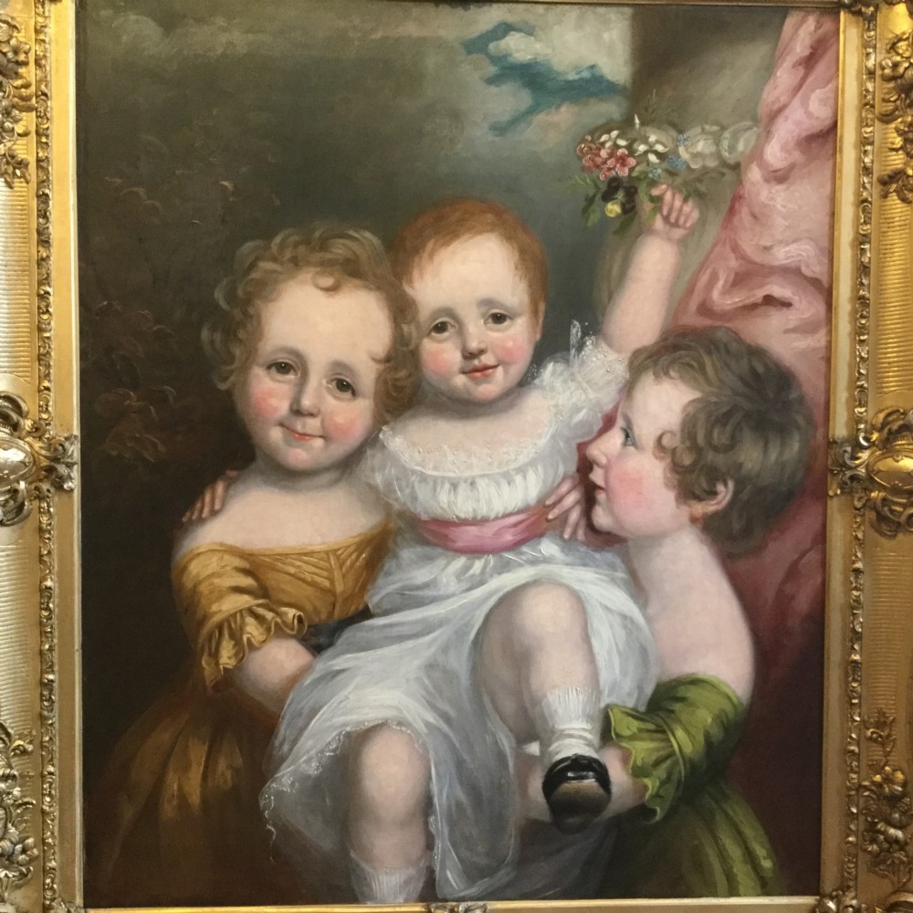 A 19th-century oil portrait of three children in classical attire contained within a carved swept giltwood frame. View II