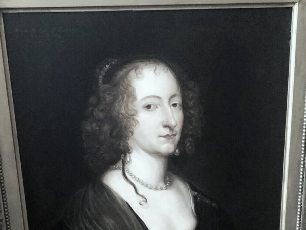 A 17th-century oil portrait depicting a noblewoman with ringlet curls wearing a dark blue gown decorated with pearls and jewelled clasps. View XII