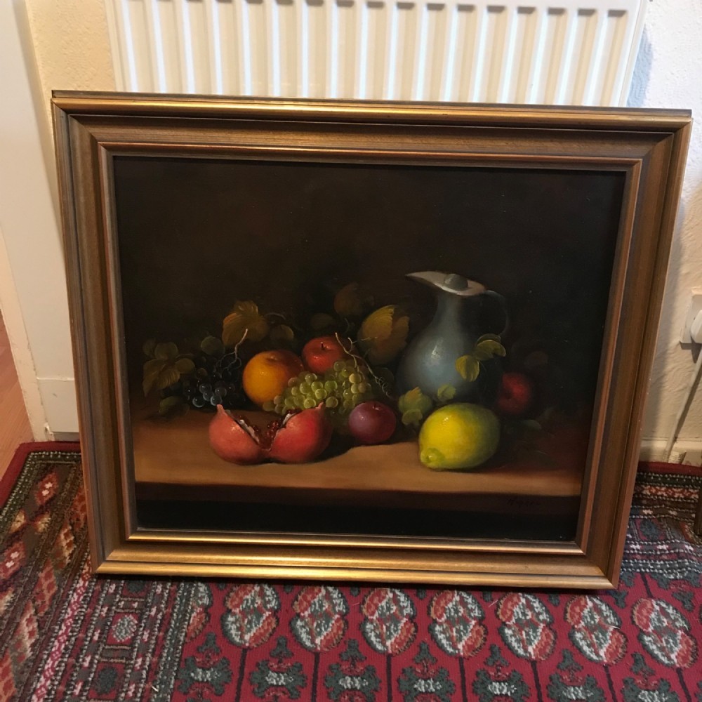 An oil painting on canvas depicting a fruit still life composition with pomegranates, grapes, apples, and a pewter jug set within a moulded gold frame. View X