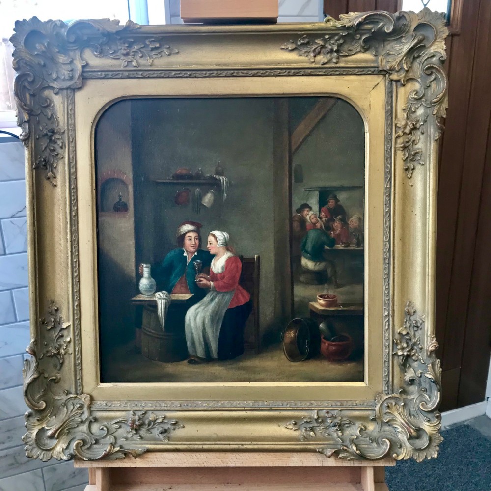 An 18th-century style oil painting depicting figures inside a tavern interior, set within a carved gold giltwood frame. View VI