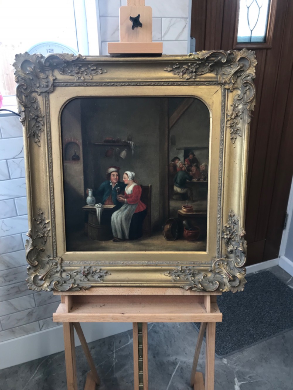 An 18th-century style oil painting depicting figures inside a tavern interior, set within a carved gold giltwood frame. View IX