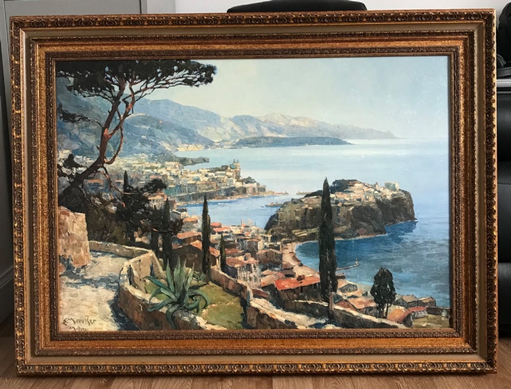 A large framed landscape print depicting a coastal vista of Monaco with cypress trees and stone walls overlooking the sea, set within a gilded frame. View III