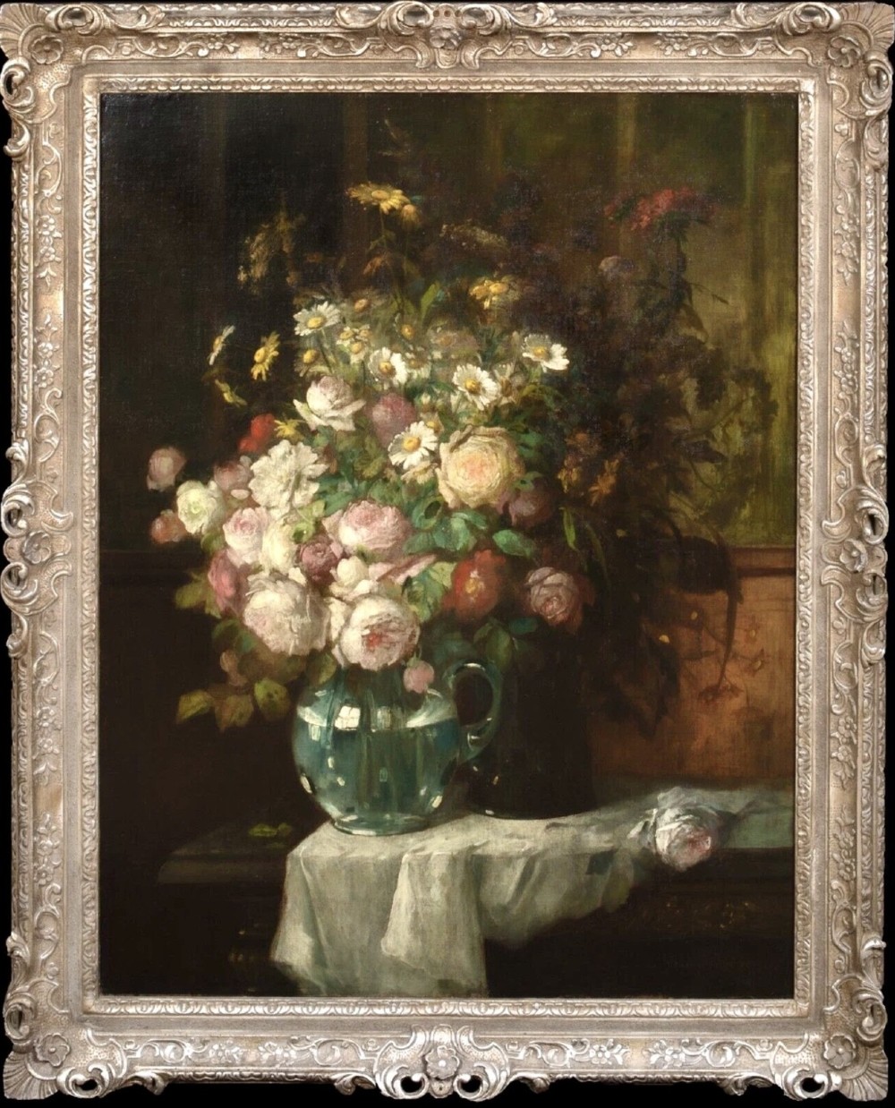 A 19th-century floral oil painting depicting a bouquet of pink and white flowers in a green glass pitcher, presented within an ornate silvered carved frame.