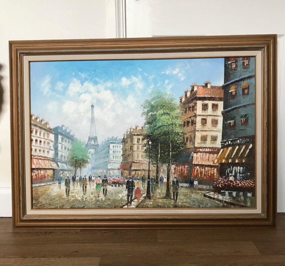 A large framed impressionist oil painting depicting a bustling Parisian street scene with buildings, figures, and the Eiffel Tower under a bright blue sky. View II