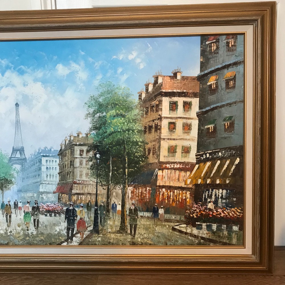 A large framed impressionist oil painting depicting a bustling Parisian street scene with buildings, figures, and the Eiffel Tower under a bright blue sky. View VI