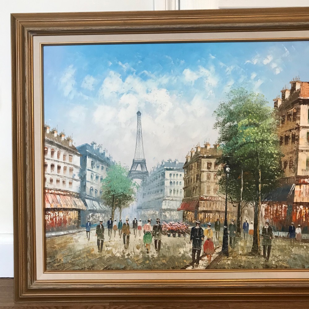 A large framed impressionist oil painting depicting a bustling Parisian street scene with buildings, figures, and the Eiffel Tower under a bright blue sky. View VII