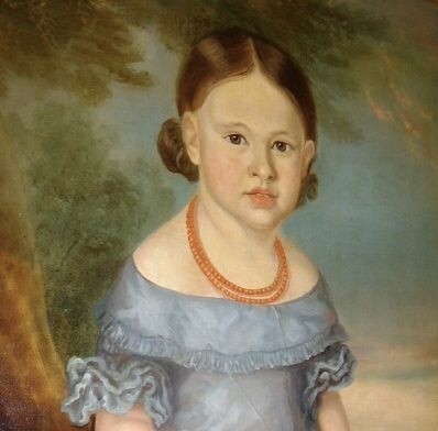 An antique oil portrait on canvas depicting a young girl in a blue dress holding a rose, displayed within a wide flame wood frame. View III