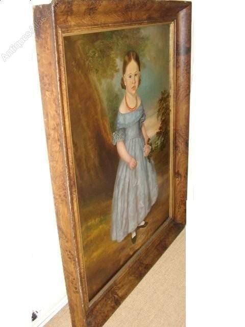 An antique oil portrait on canvas depicting a young girl in a blue dress holding a rose, displayed within a wide flame wood frame. View VIII
