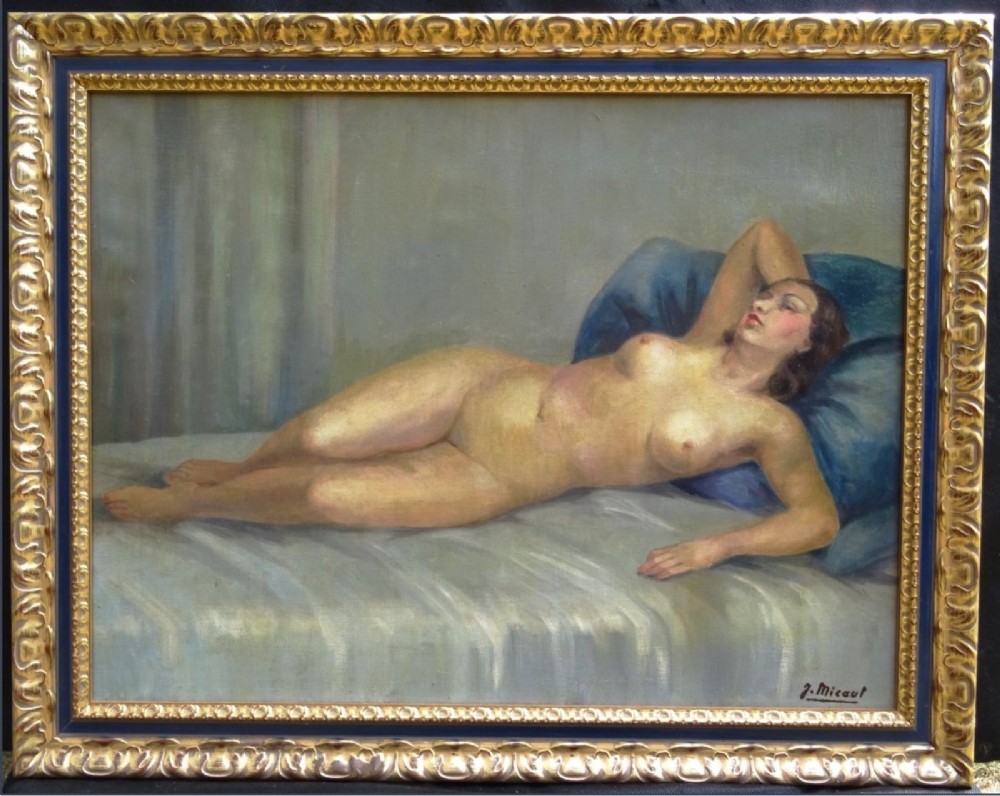A framed French Art Deco oil painting on canvas depicting a reclining female nude resting against a blue pillow.