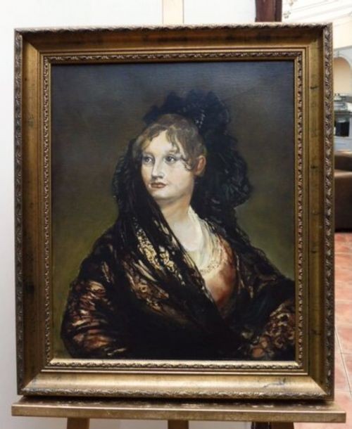 A portrait oil painting depicting a lady in a black lace mantilla set within a moulded gilt wood frame.