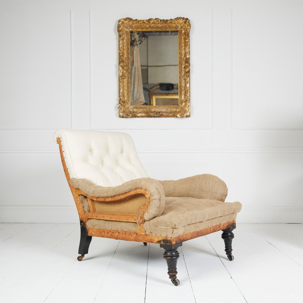 A Victorian Howard style armchair upholstered in cream buttoned calico and brown hessian with turned front legs on brass castors.