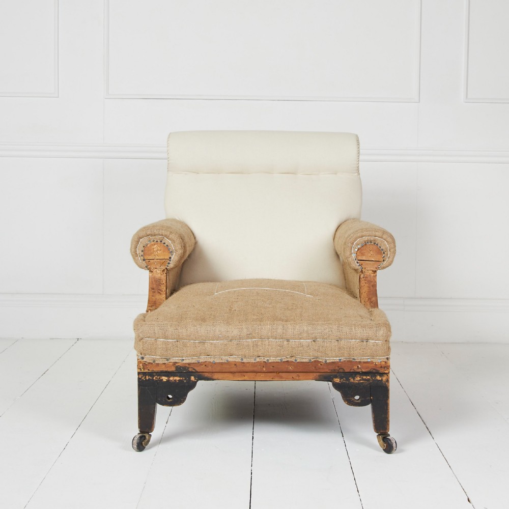 A Victorian scroll-back armchair featuring exposed deconstructed hessian upholstery, a cream fabric back roll, turned dark legs, and brass castors. View III