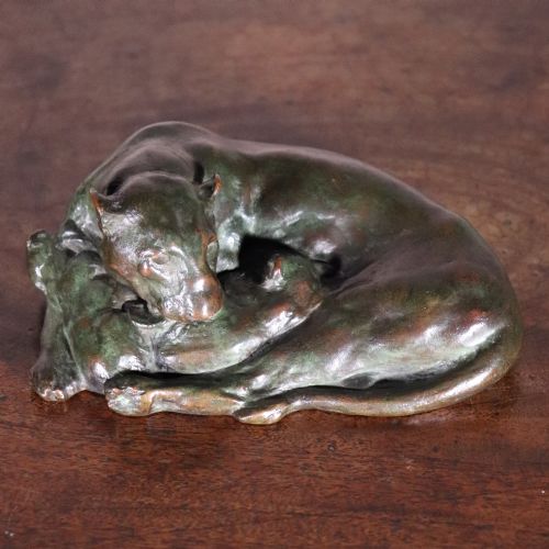 fig 2. A cast bronze sculpture depicting a recumbent lioness with a dark green verdigris patina resting on a flat surface.