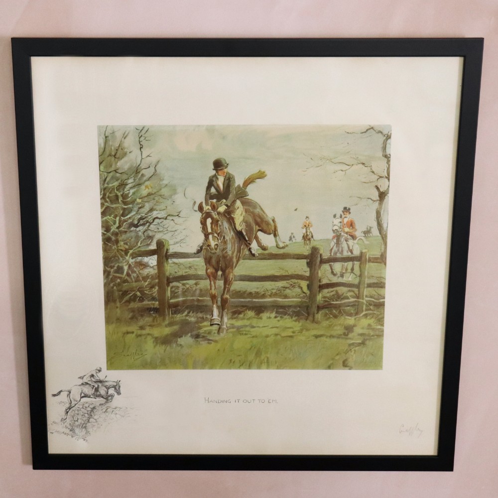 A framed equestrian print depicting a horse and rider leaping a timber fence, presented in a black frame with an off-white mount and margin remarque.