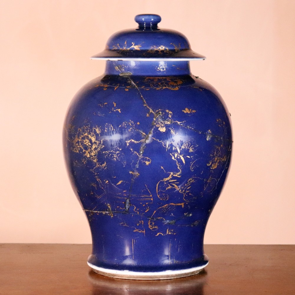 An early 19th-century Chinese powder blue porcelain jar featuring a domed cover, gilded floral decoration, and visible metal staple repairs.