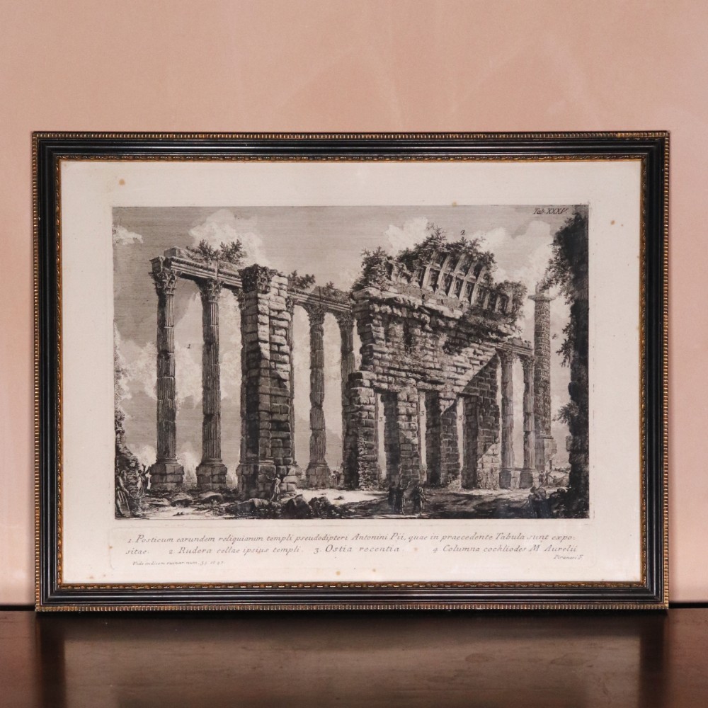 A framed eighteenth-century monochrome etching depicting ancient Roman temple ruins with classical columns, set inside a black moulded wooden frame.