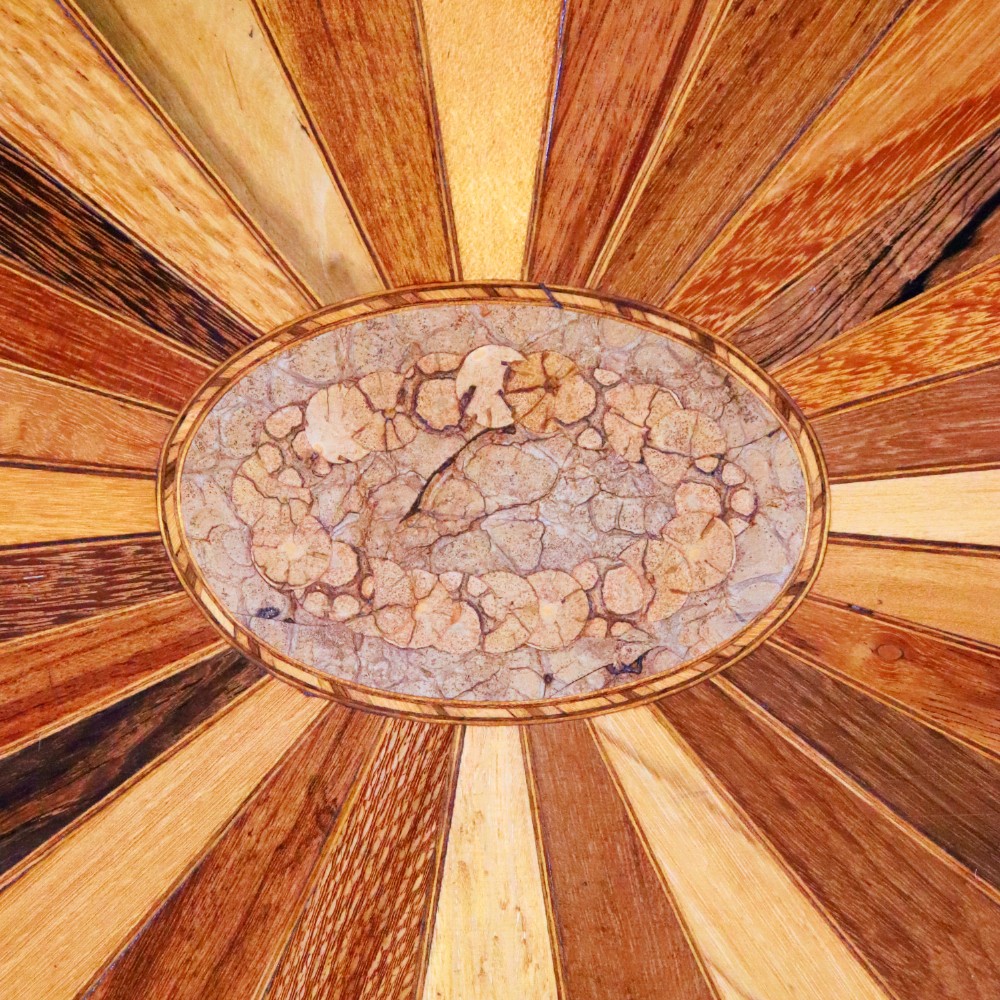 An oval antique tray featuring a central sunburst parquetry design of contrasting specimen woods with carved side handles. View V