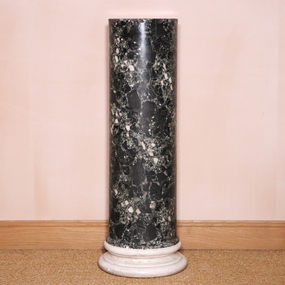 An early nineteenth-century cylindrical scagliola column pedestal with a dark green speckled faux-marble finish resting on a moulded off-white circular base.