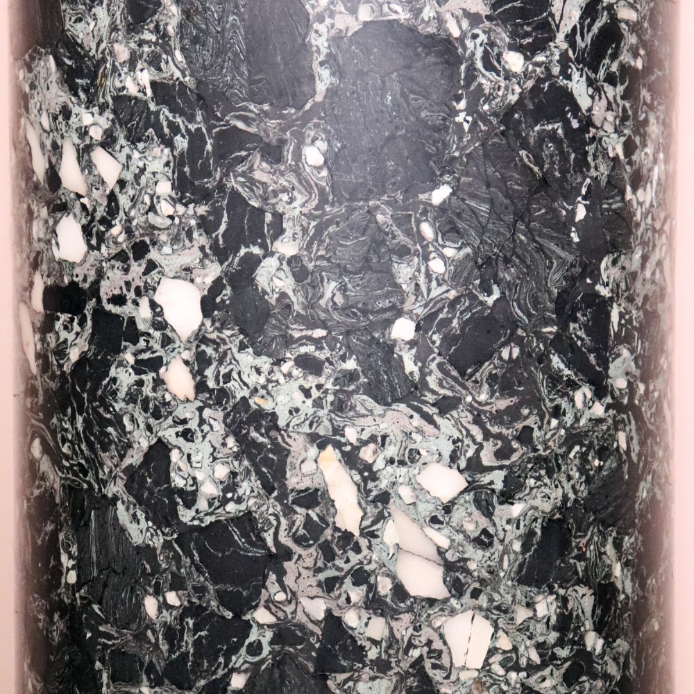 An early nineteenth-century cylindrical scagliola column pedestal with a dark green speckled faux-marble finish resting on a moulded off-white circular base. View V