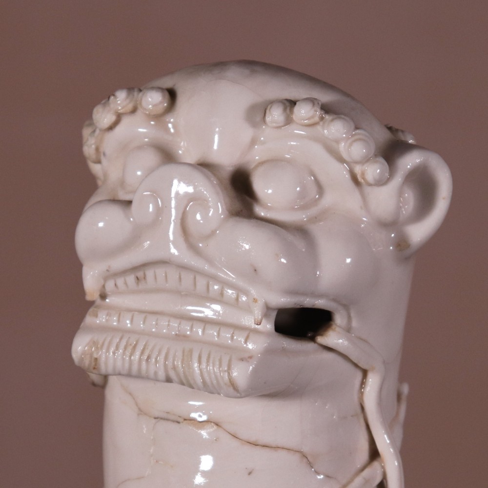 A pair of 18th-century cream-glazed Blanc de Chine porcelain guardian lion statues seated upright on rectangular bases. View IV