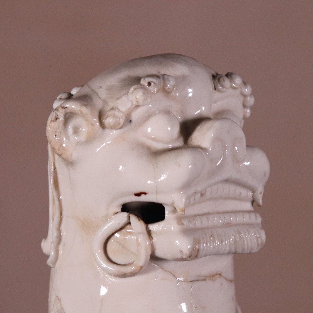 A pair of 18th-century cream-glazed Blanc de Chine porcelain guardian lion statues seated upright on rectangular bases. View V