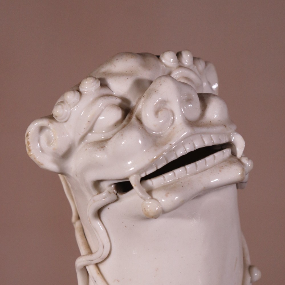 A pair of 18th-century cream-glazed Blanc de Chine porcelain guardian lion statues seated upright on rectangular bases. View VI