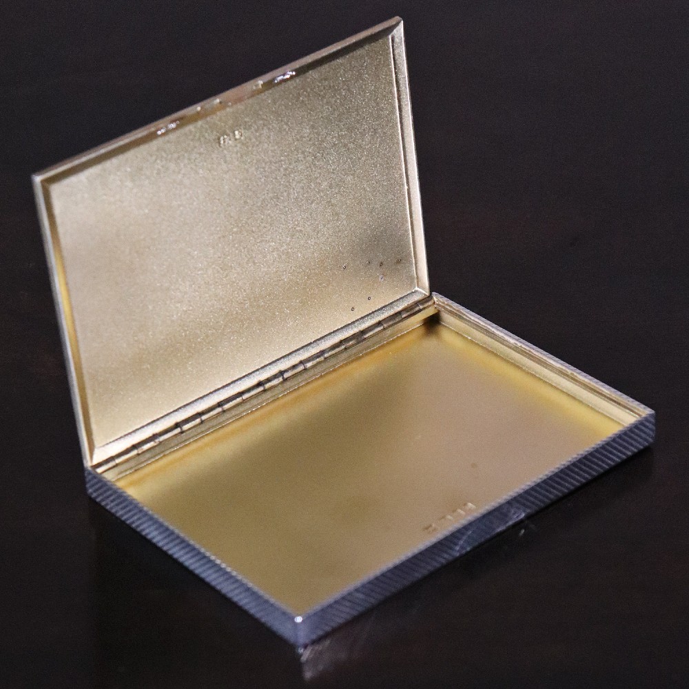 An engine-turned silver and gold mounted Cartier notelet case presented inside an open red leather fitted box alongside written correspondence. View VII