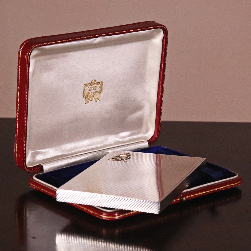 An engine-turned silver and gold mounted Cartier notelet case presented inside an open red leather fitted box alongside written correspondence. View XIII