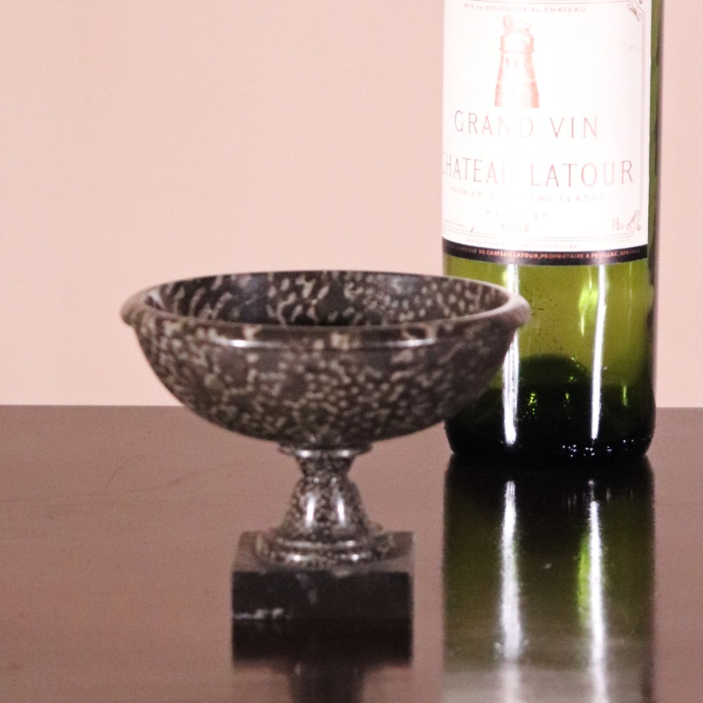 A small nineteenth-century tazza carved from dark Ashford coral marble with visible light fossil inclusions, featuring a shallow round bowl on a turned pedestal and square plinth base. View IX
