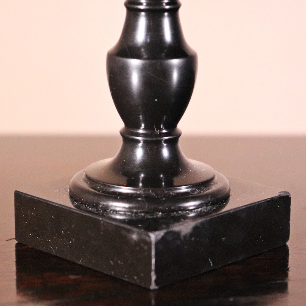 A nineteenth-century Ashford black marble miniature table featuring a round top inlaid with colourful geometric marble specimens, supported by a turned baluster column on a square plinth base. View II