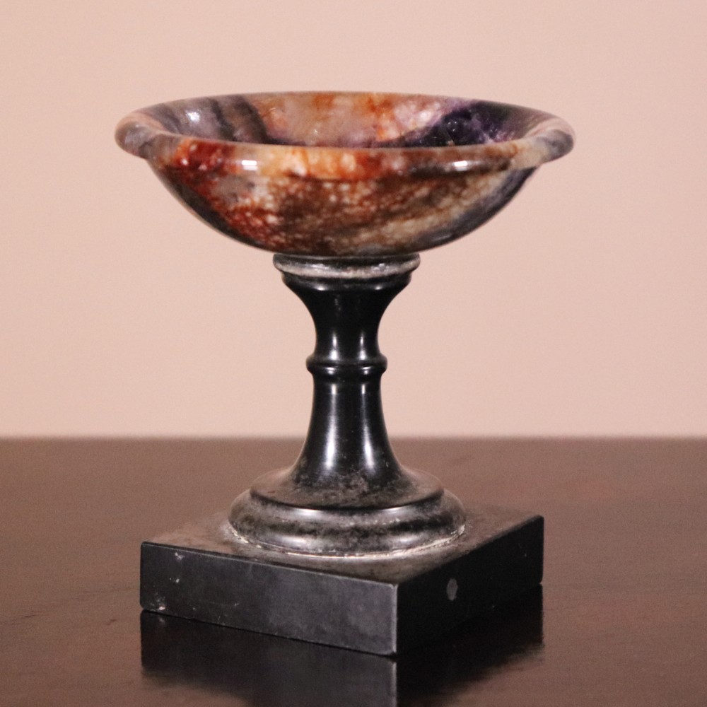 A small nineteenth-century tazza featuring a shallow turned Blue John bowl with purple and brown banding, set upon a black turned marble stem and square base. View II