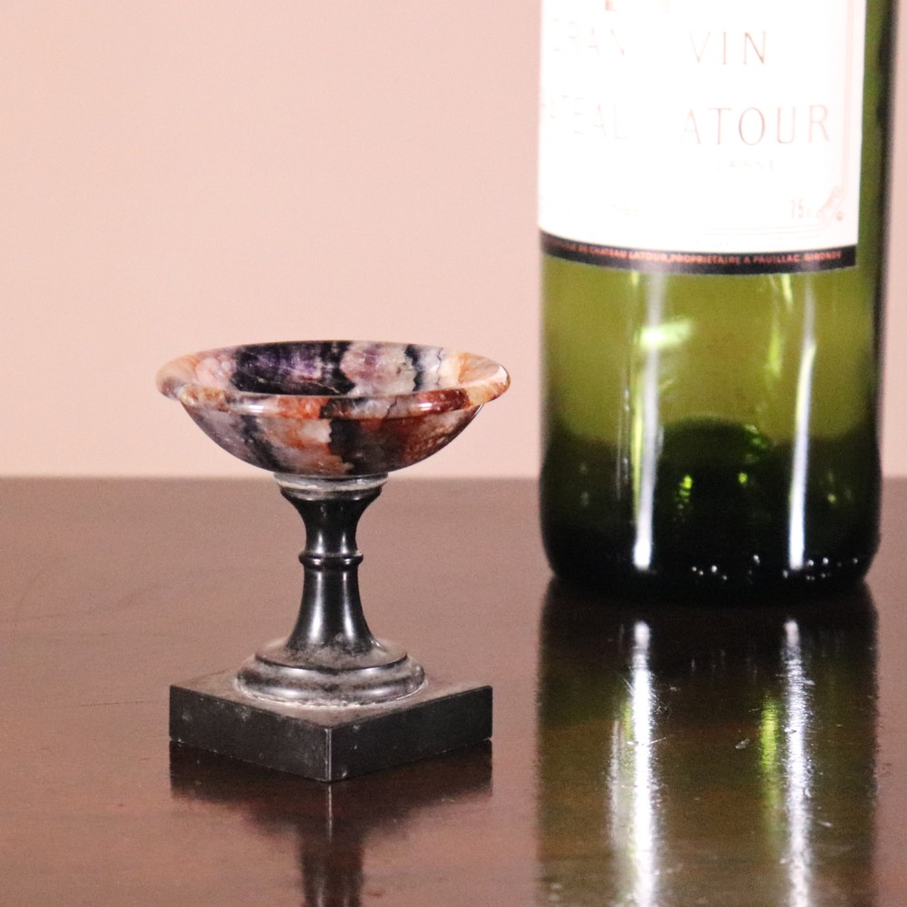 A small nineteenth-century tazza featuring a shallow turned Blue John bowl with purple and brown banding, set upon a black turned marble stem and square base. View VIII
