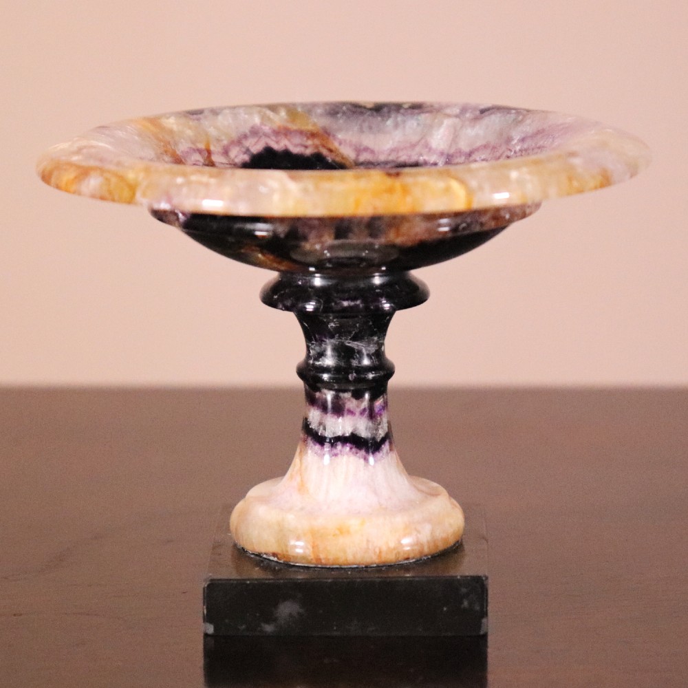A small 19th-century Blue John fluorite tazza with purple and yellow banding, mounted on a turned stem and a square black marble base.