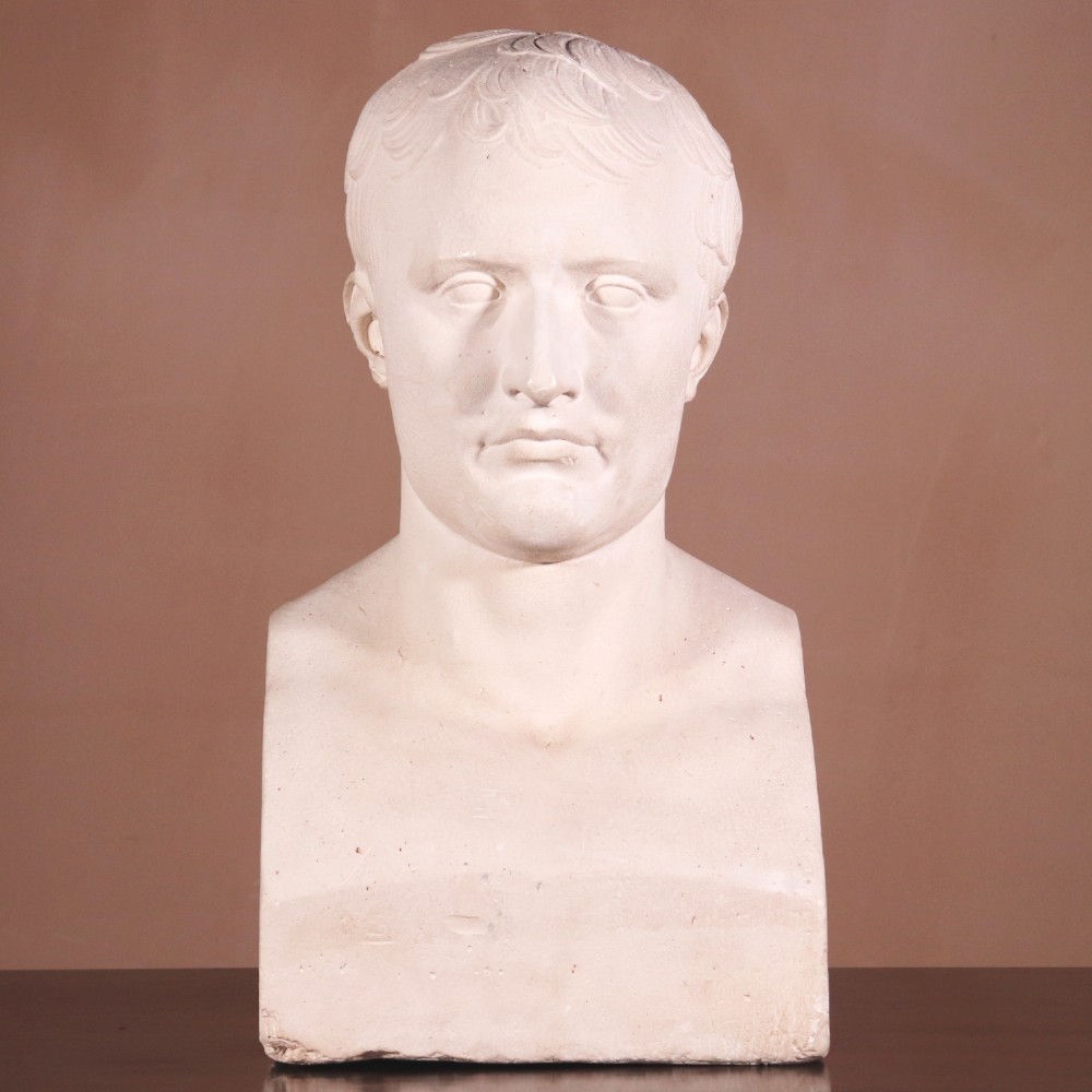 An off-white plaster portrait bust depicting Napoleon Bonaparte with short classical hair and a square pedestal base.