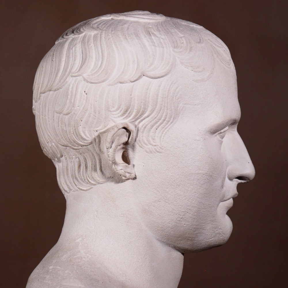An off-white plaster portrait bust depicting Napoleon Bonaparte with short classical hair and a square pedestal base. View IV