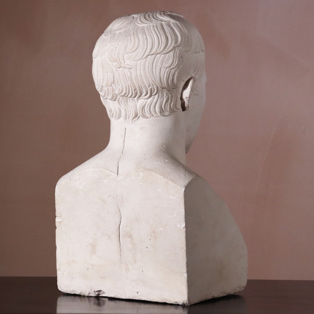 An off-white plaster portrait bust depicting Napoleon Bonaparte with short classical hair and a square pedestal base. View VI