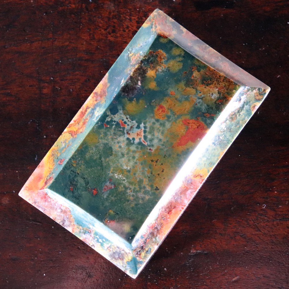 A rectangular nineteenth-century agate paperweight featuring bevelled edges and a mottled surface of deep green, ochre, and rust red tones.