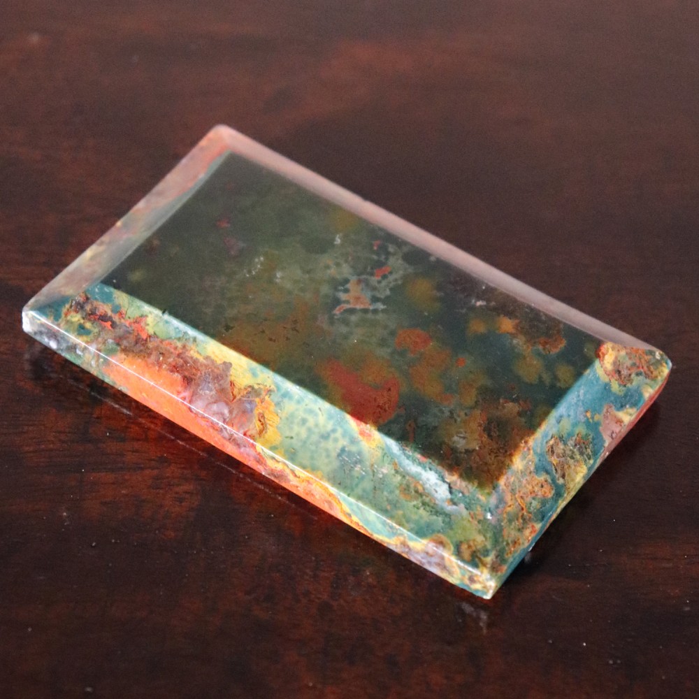 A rectangular nineteenth-century agate paperweight featuring bevelled edges and a mottled surface of deep green, ochre, and rust red tones. View II