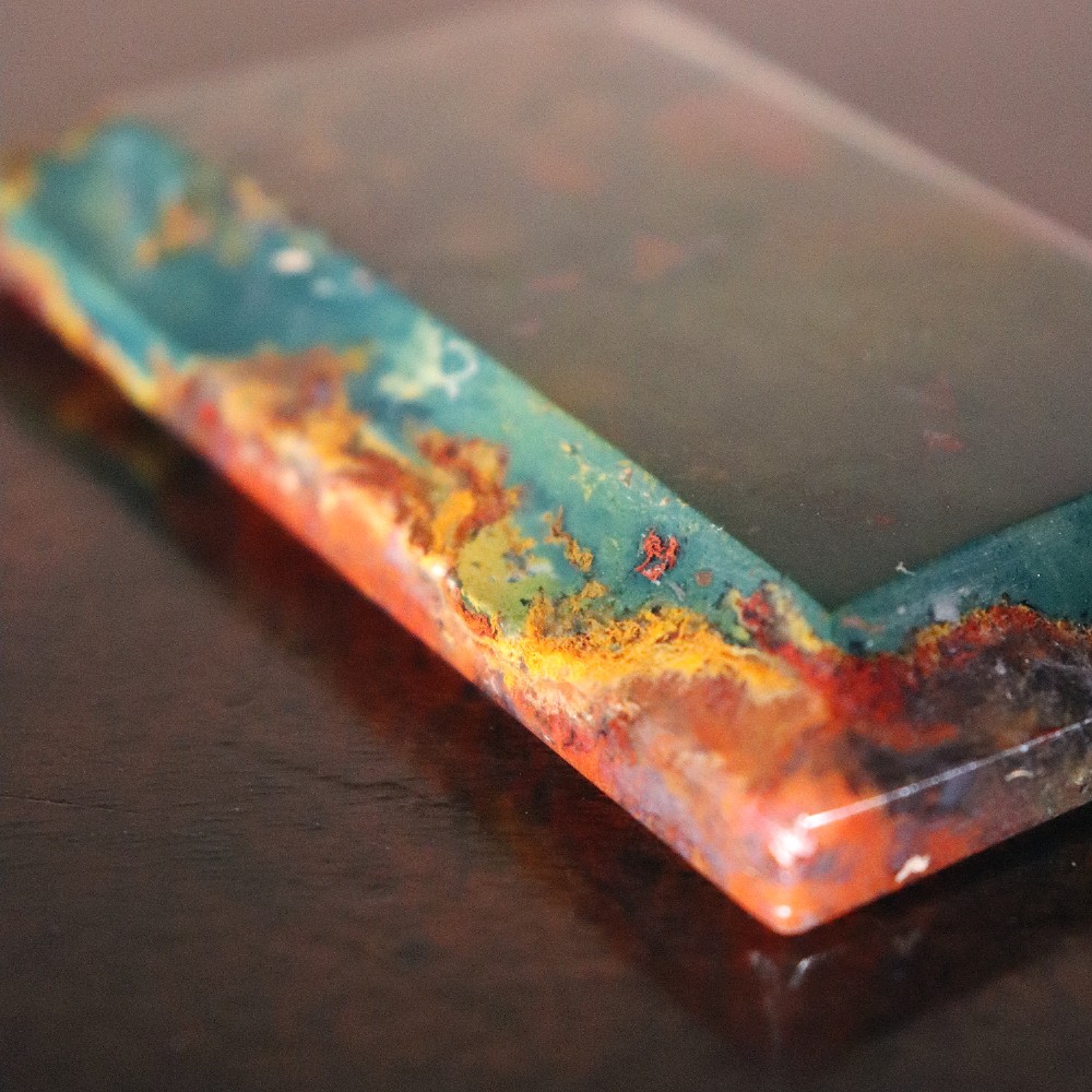 A rectangular nineteenth-century agate paperweight featuring bevelled edges and a mottled surface of deep green, ochre, and rust red tones. View III