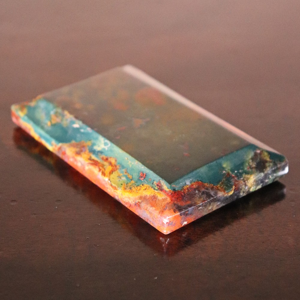 A rectangular nineteenth-century agate paperweight featuring bevelled edges and a mottled surface of deep green, ochre, and rust red tones. View V