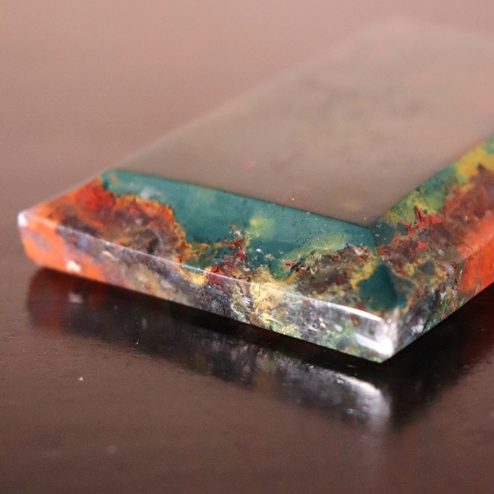 A rectangular nineteenth-century agate paperweight featuring bevelled edges and a mottled surface of deep green, ochre, and rust red tones. View VII