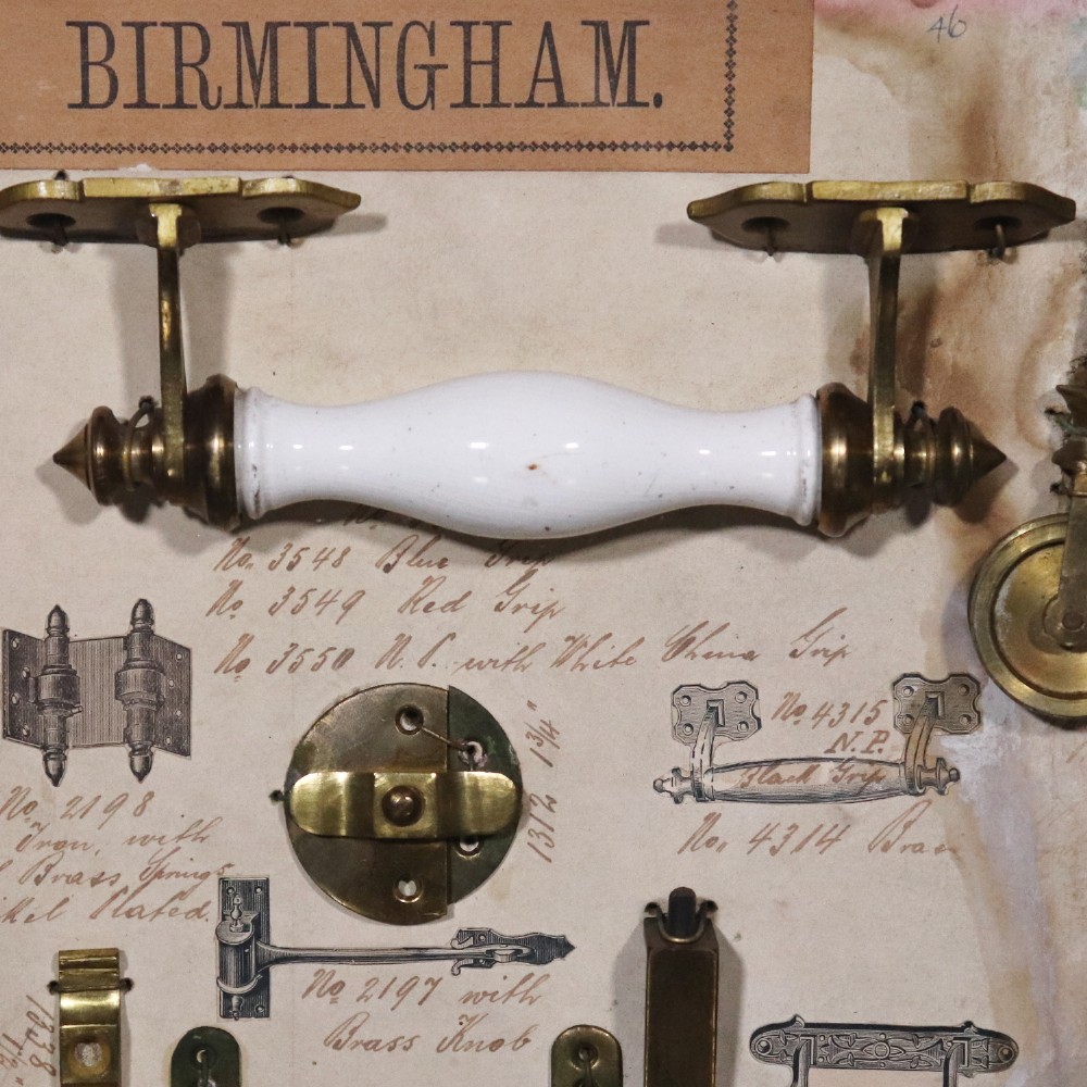 A framed commercial sample board containing antique brass and cast iron door hardware, latches, and ceramic handles mounted on annotated paper with a header reading Gerwin & Co., Birmingham. View IV
