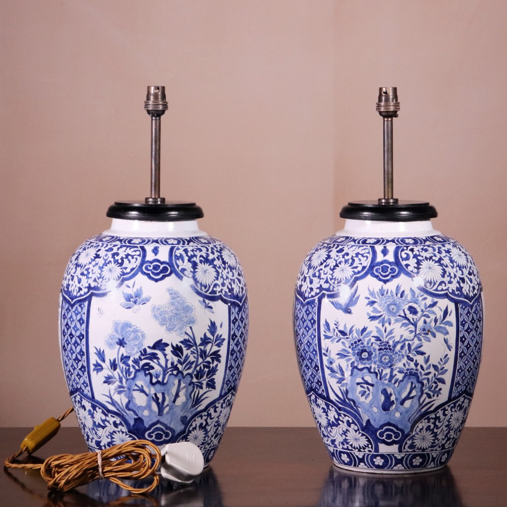 A pair of Chinese style blue and white porcelain ginger jar table lamps featuring floral panels mounted on dark wooden bases. View VI