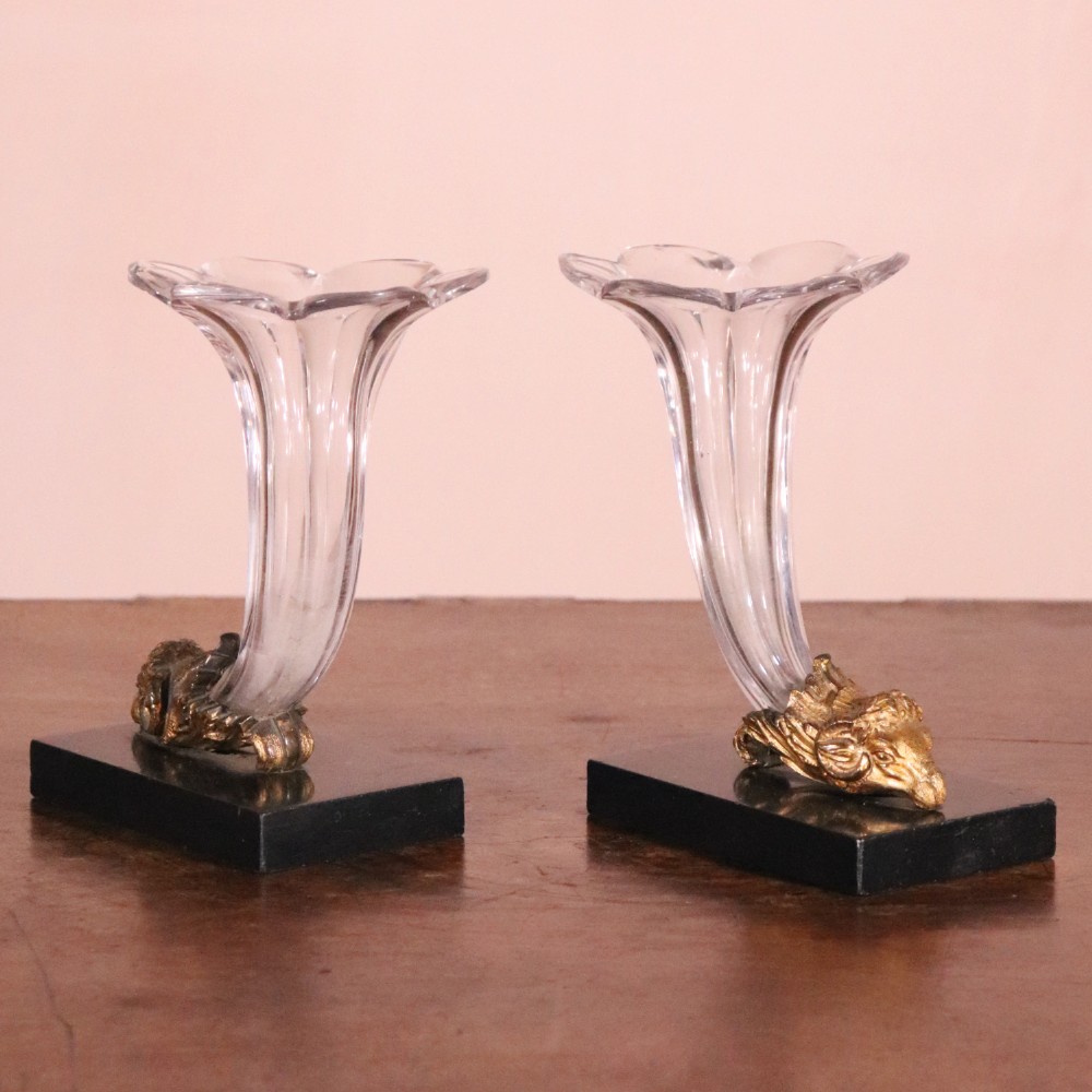 A pair of Regency cornucopia vases featuring fluted clear glass horns set into gilt bronze rams head mounts on rectangular black marble bases. View III