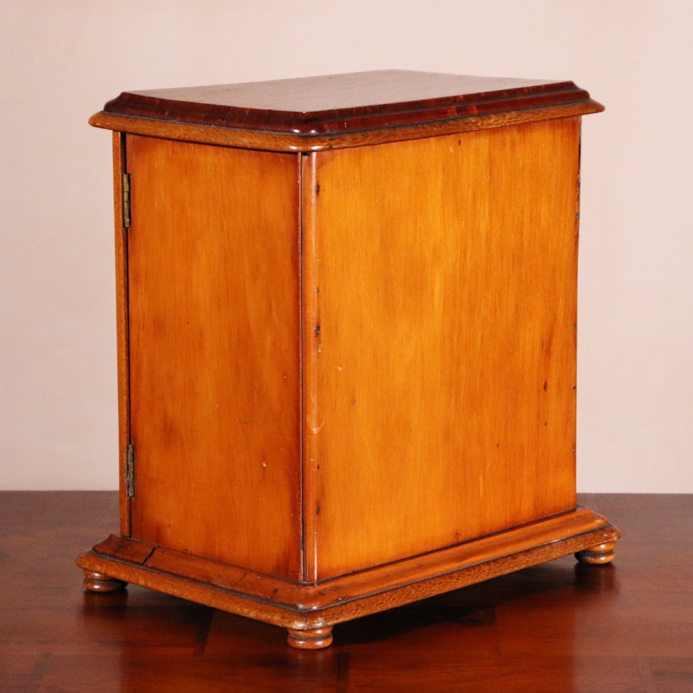 A 19th-century wooden table cabinet with two doors featuring inlaid star motifs set within pointed arches, resting on turned bun feet. View VIII