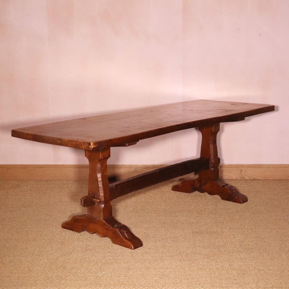 A handcrafted oak trestle dining table featuring an adzed tabletop, keyed stretcher joint, and two matching solid oak benches. View III
