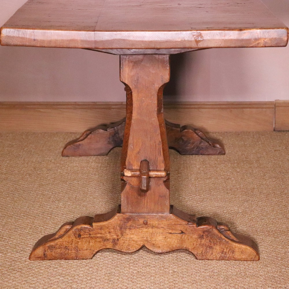 A handcrafted oak trestle dining table featuring an adzed tabletop, keyed stretcher joint, and two matching solid oak benches. View IV